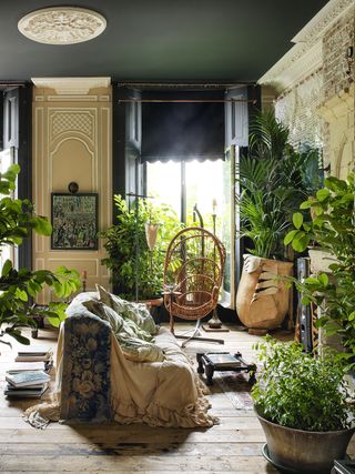 boho living room filled with house plants in big pots and a white sofa