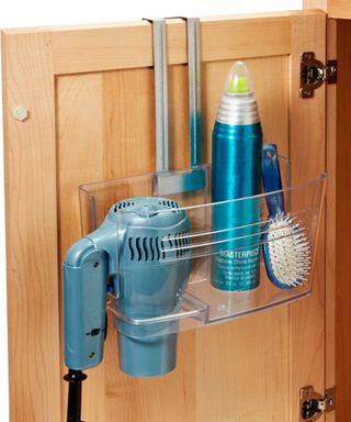 A clear door organizer with blue hairdryer, hair product and brush