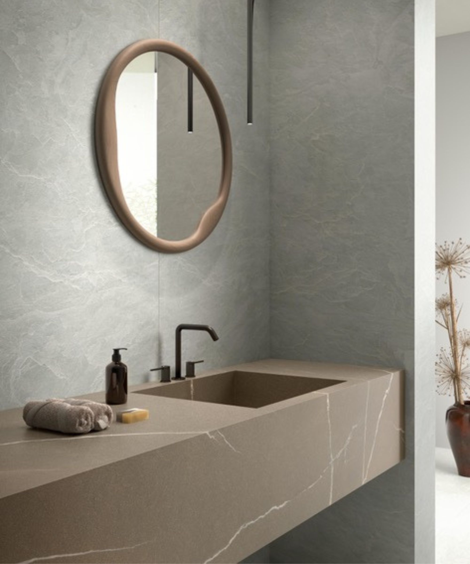 A modern bathroom vanity with a circular mirror a faux marble floating sink and natural slate effect wall panels