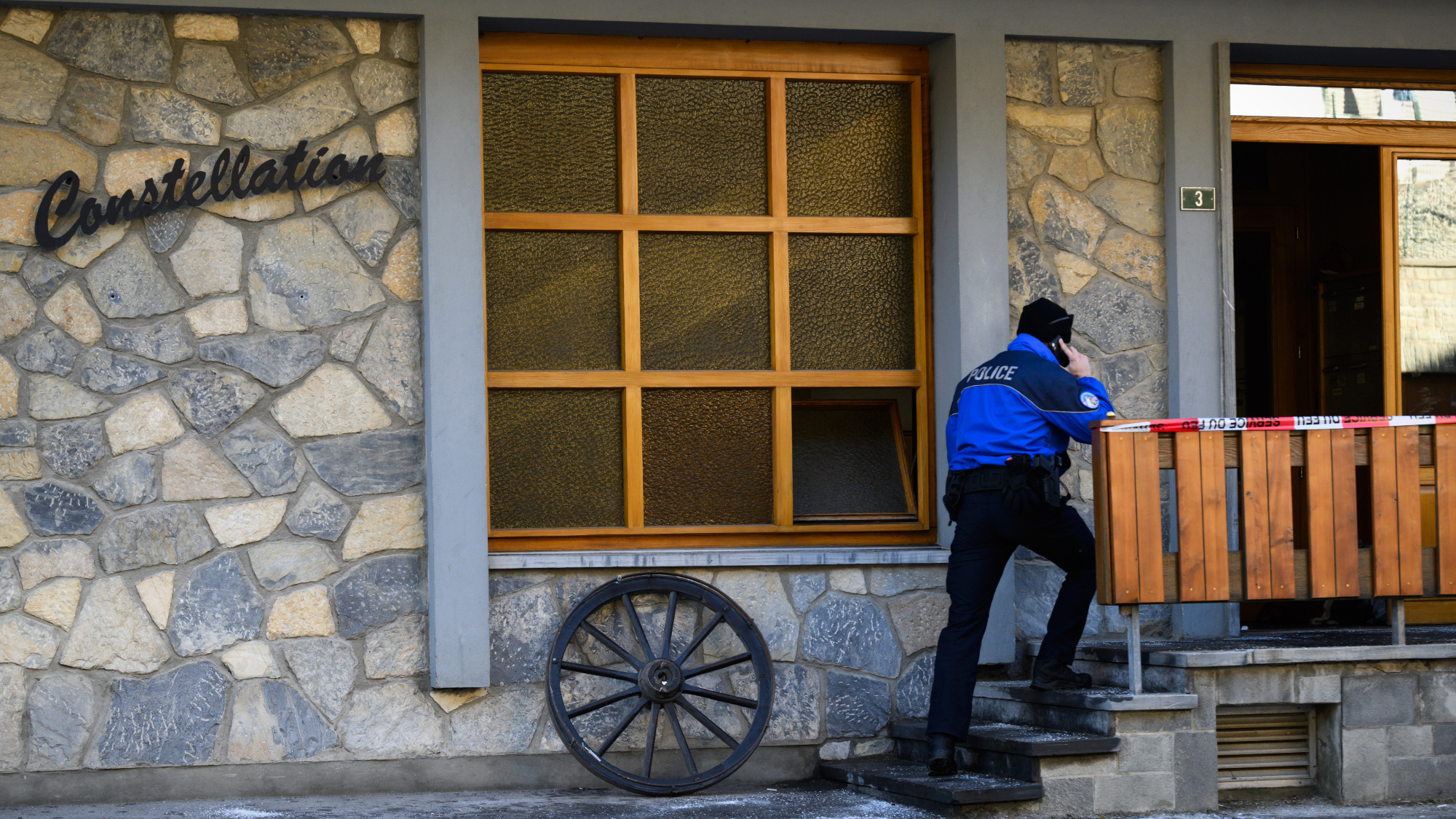 Police officer enters rear entrance to Swiss night club Le Constellation after deadly fire
