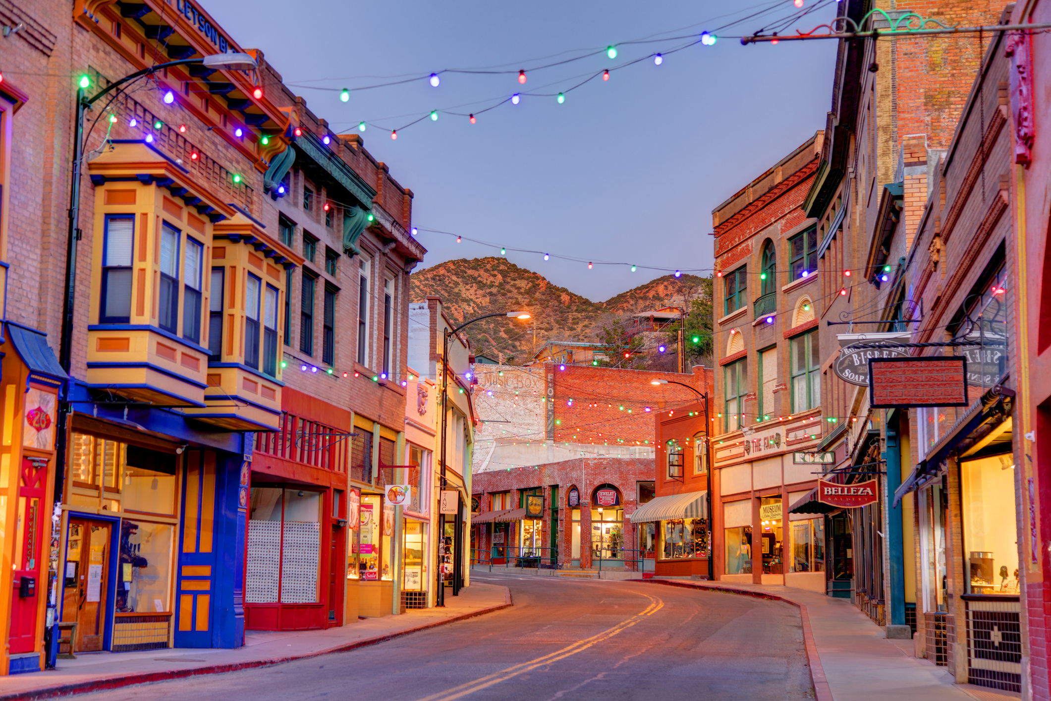 The city of Bisbee in Cochise County, Arizona, at twilight, with brightly colored buildings and string lights.