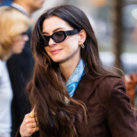 Anne Hathaway in The Devil Wears Prada 2 wearing Levi's vintage denim jeans with a brown suede jacket and snakeskin heeled boots