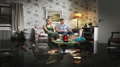 A couple sits in a flooded room.