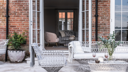 Patio area with paving, garden furniture and french doors outside a converted Victorian coachhouse.