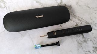 Philips Sonicare DiamondClean 9000 with brush head detached, next to charging case