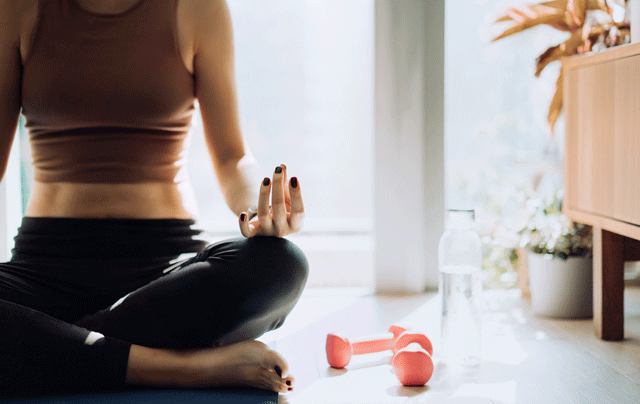 woman meditating with dumbbells on floor