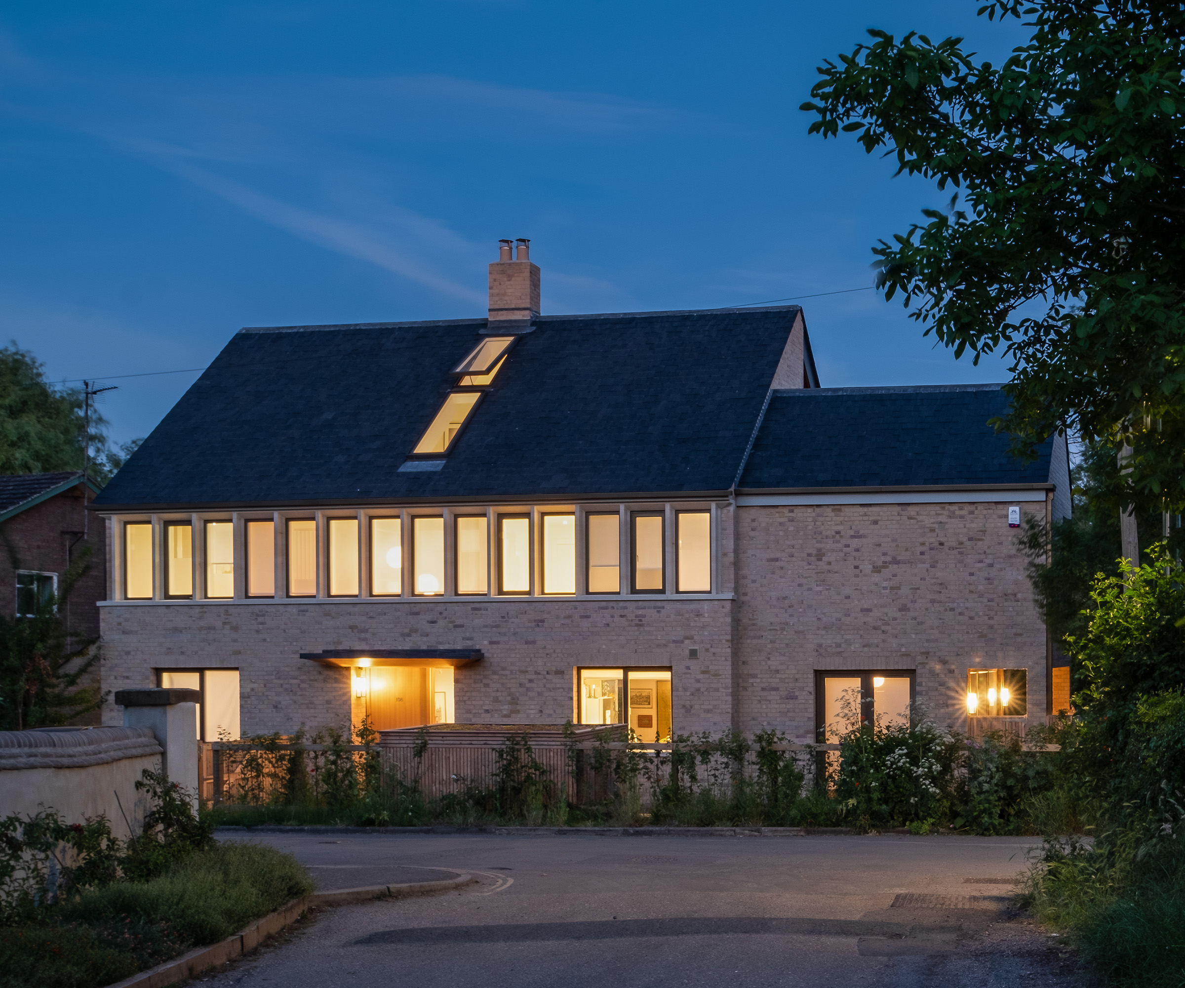 A light stone self build home at dusk with interior lights on