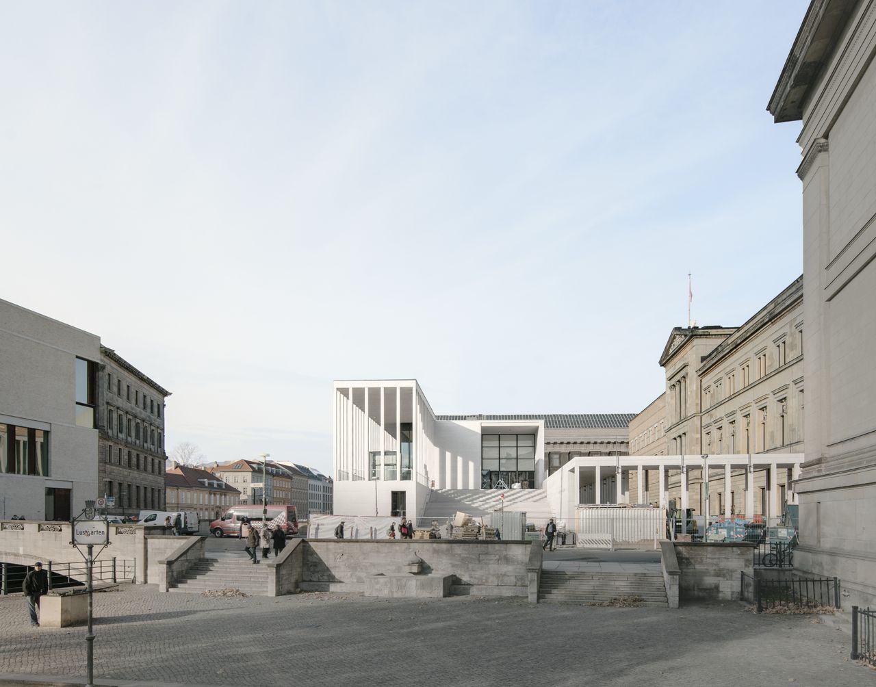 A photo of the James Simon Galerie from across the street. The building is all white. The left side has tall slender pillaras. In the middle there is a grand staircase.