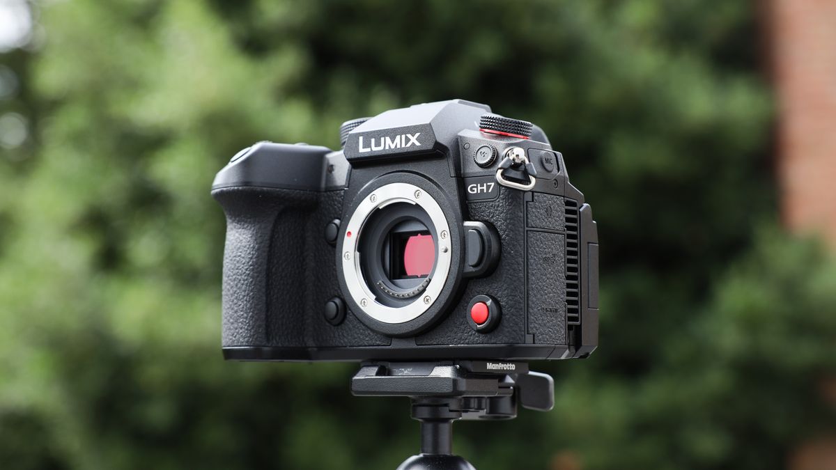 Panasonic Lumix GH7 on a tripod outside with some blurred green trees in the background
