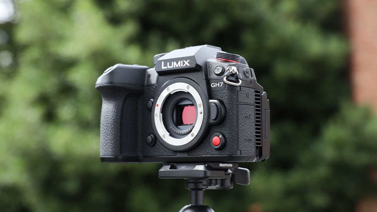 Panasonic Lumix GH7 on a tripod outside with some blurred green trees in the background