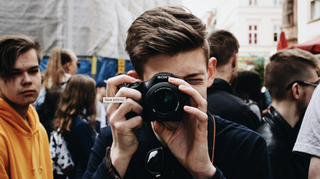 Photo of man taking picture in street