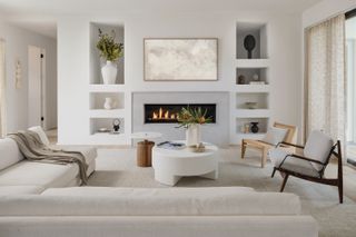 A taupe and white living room with sofas around a fireplace