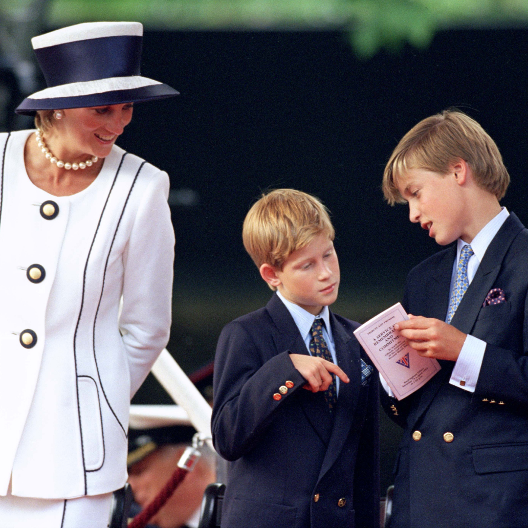 Princess Diana wearing a white suit and hat smiling at Prince Harry and Prince William, who are looking at a program