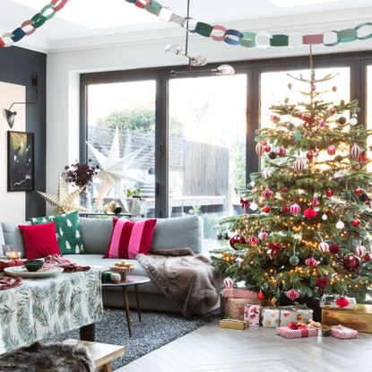 Living room with decorated Christmas tree, presents, and cushions