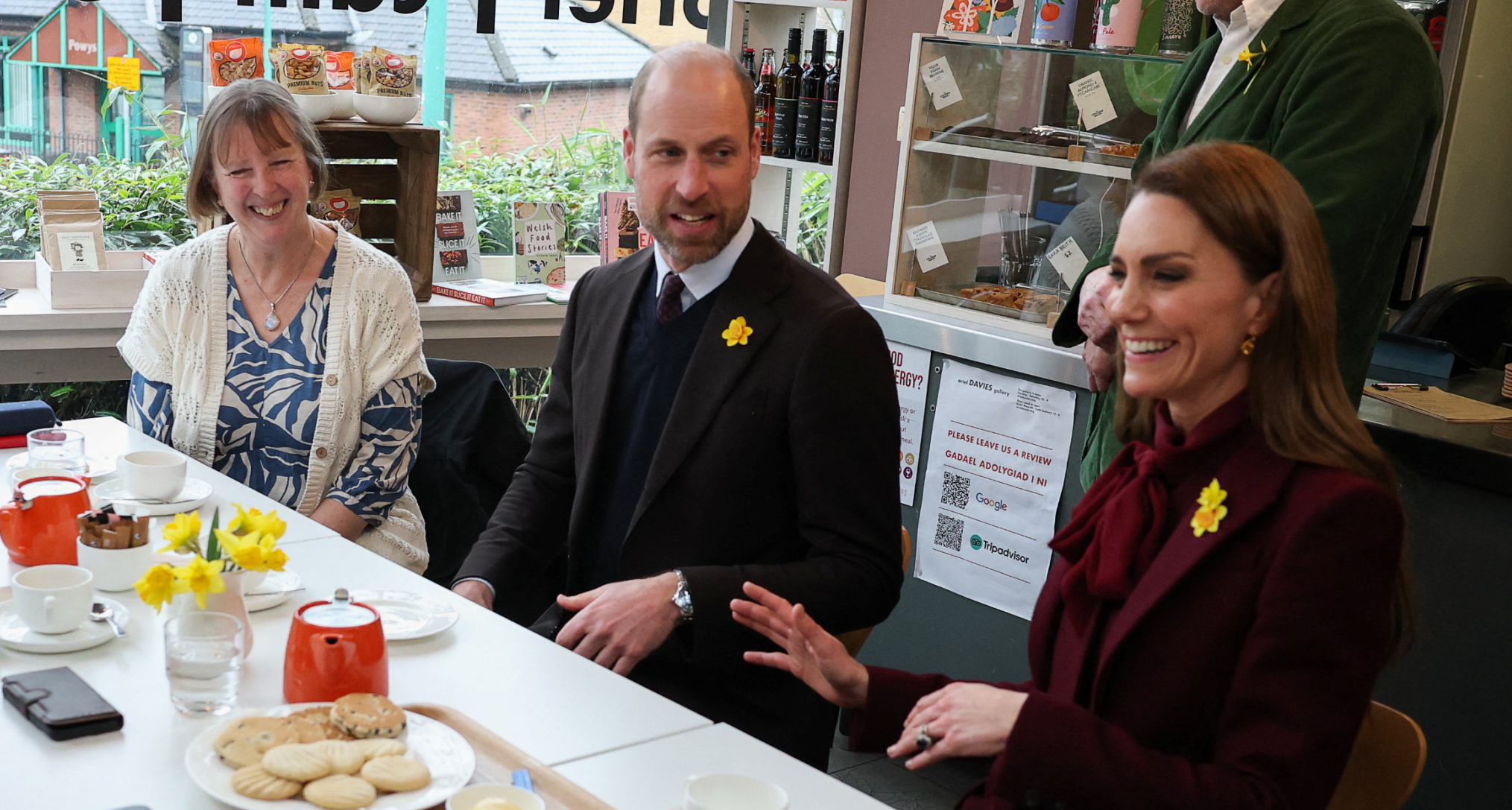 Prince William and Princess Kate sitting at a table with a woman at a cafe