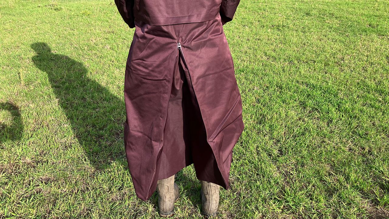 Lady wears LeMieux All Elements Robe in a field, close up of riding vent viewed from the back