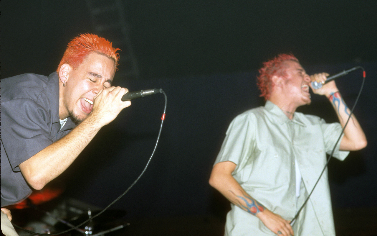 Mike Shinoda and Chester Bennington, both with dyed red hair, singing on stage in 2000