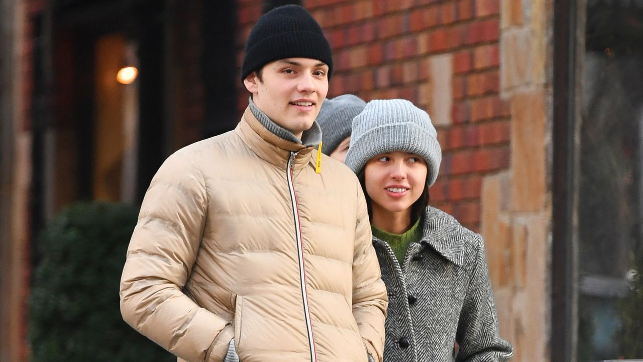 Olivia Rodrigo and Louis Partridge wearing coats and sneakers