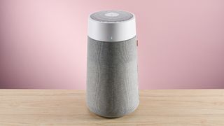 The large Blueair air purifier sits facing forward on a wood surface against a pink background.