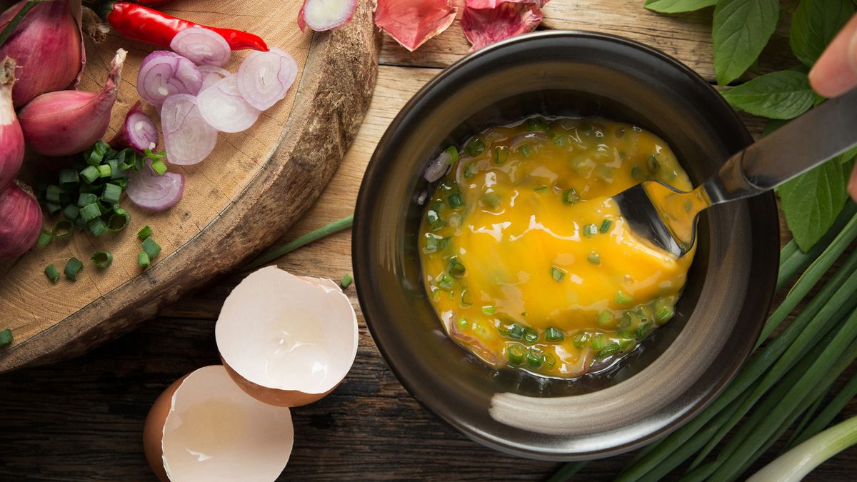 raw eggs and chives in a black bowl