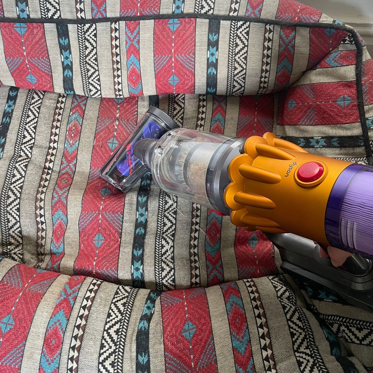 Using the Dyson hair screw tool on a red and grey aztec dog bed