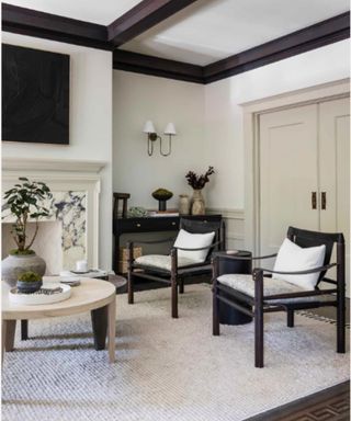 A white living room with dark wood furniture with an open silhouette and dark ceiling beams