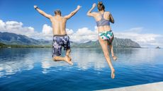 Man and women jumping together into the ocean while on a beautiful scenic Hawaiian vacation. Thrilling and exciting experience. Concept about holiday, success, accomplishment and lifestyle