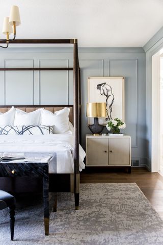 Pale blue bedroom with panelled walls and four poster bed