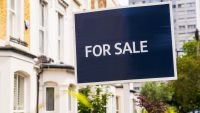 Close-up of a blue 'For Sale' real estate agent's sign in Islington, London.