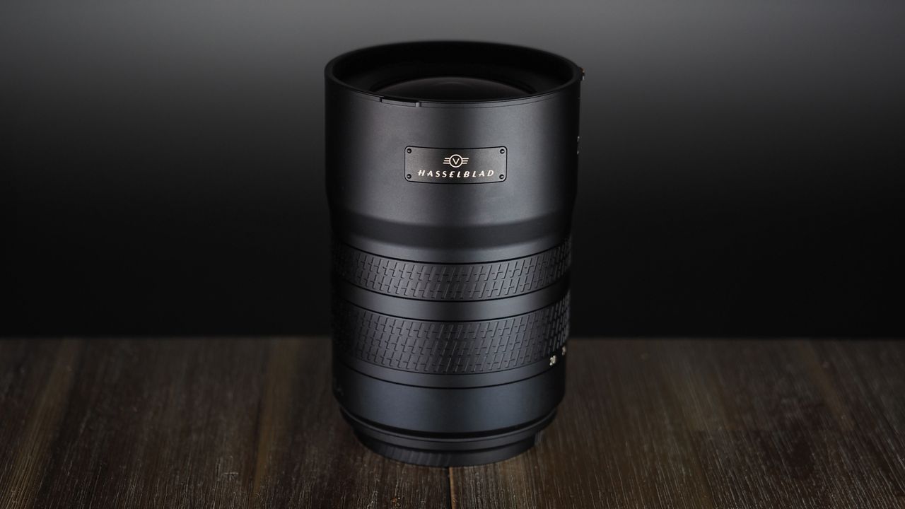 Hasselblad XCD 20-35E lens, moodily lit with subdued lighting, on a wooden surface