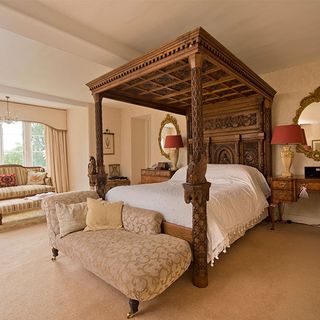 bedroom with cream coloured wall and four poster with bed