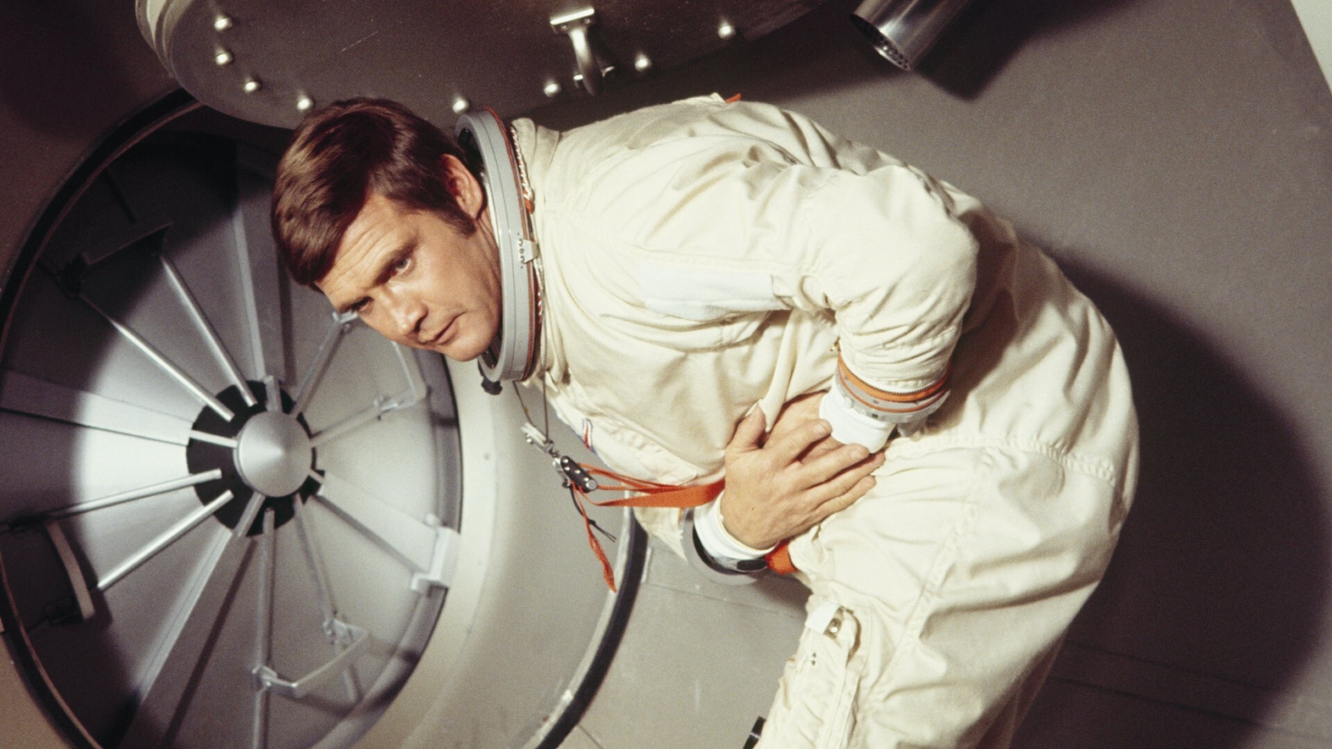 A man in space holding his stomach.