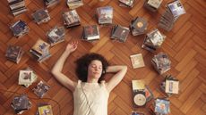 Woman lying on floor, listening to CDs