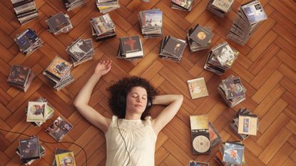 Woman lying on floor, listening to CDs