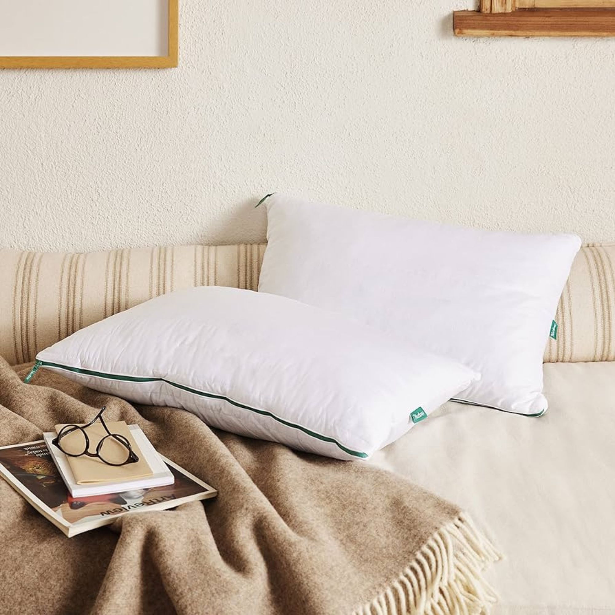 The Marlow Pillow on a bed against a cream wall.