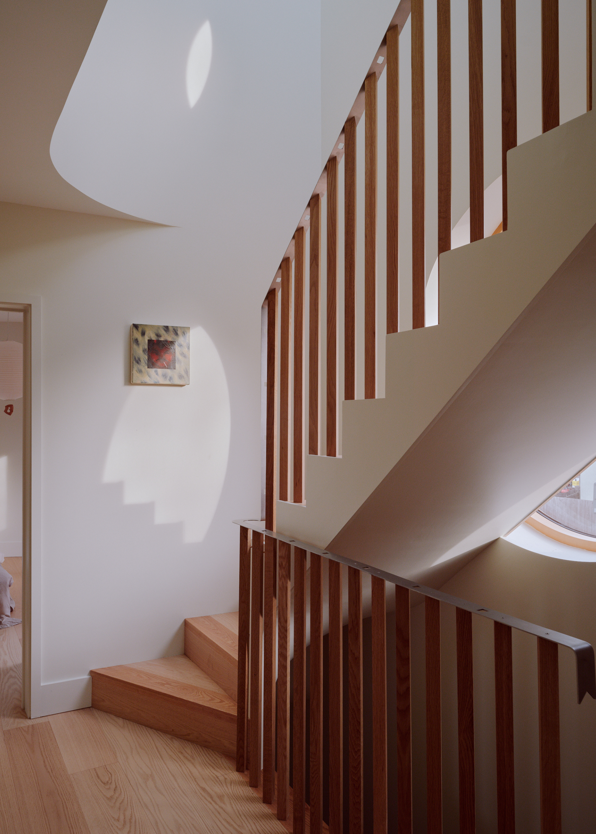 wooden staircase in a house with curved walls and round windows
