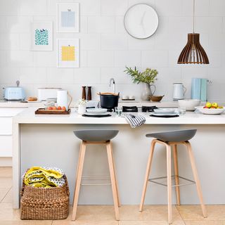 Kitchen isalnd with grey bar stools, wooden pendant light and woven basket on floor