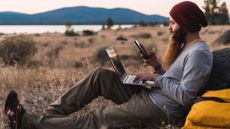 Man using laptop and smartphone outdoors