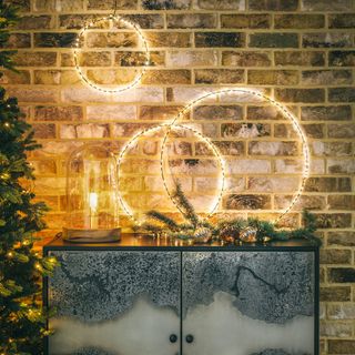 illuminated Christmas LED rings on brick wall above a metal sideboard