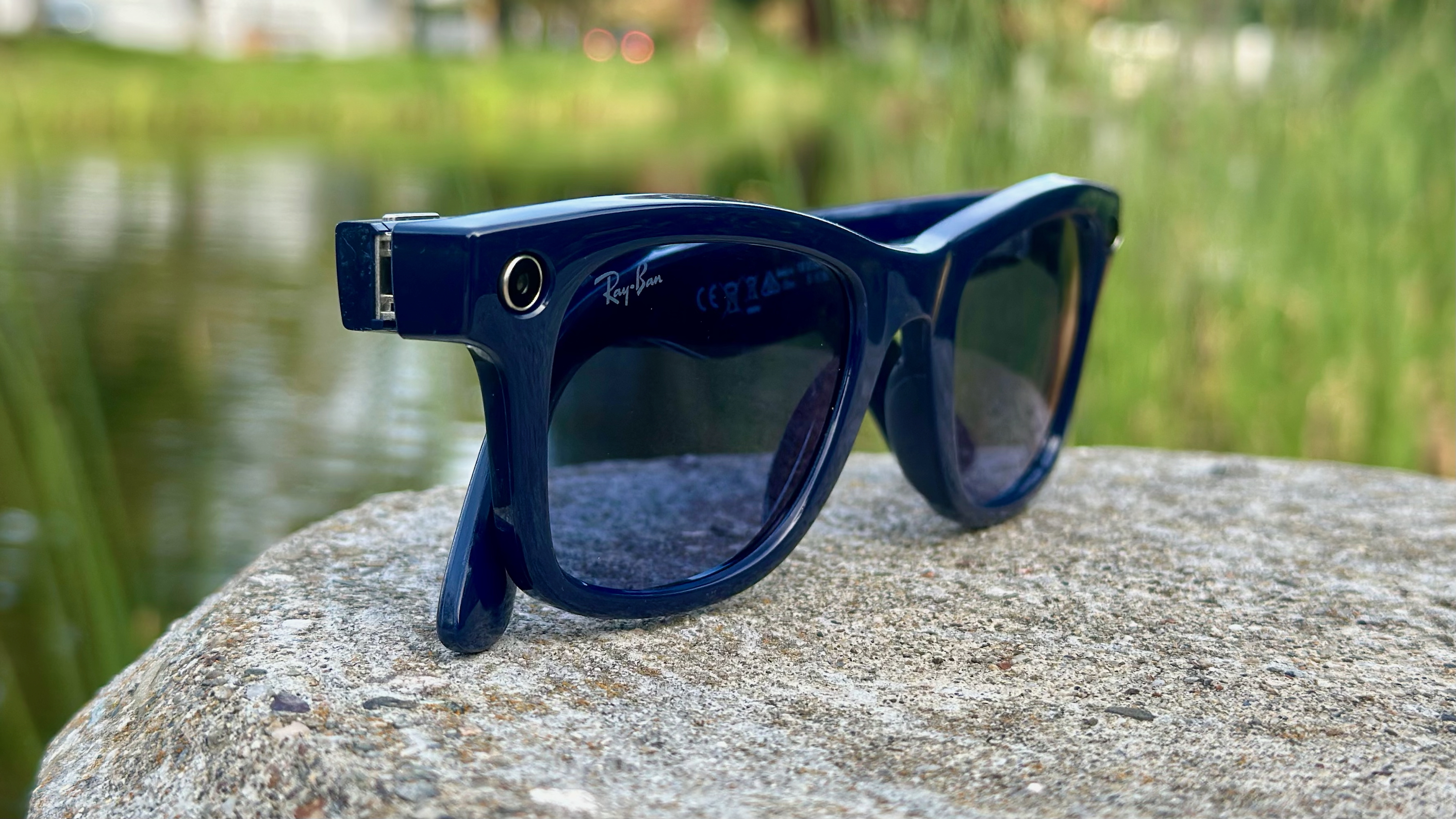 A photo of the Ray-Ban Meta (Gen 2) smart glasses sitting on a rock, angled to focus on the right camera cutout.