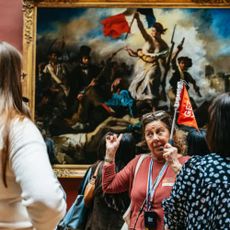 Tour guide woman pointing to painting in the Louvre
