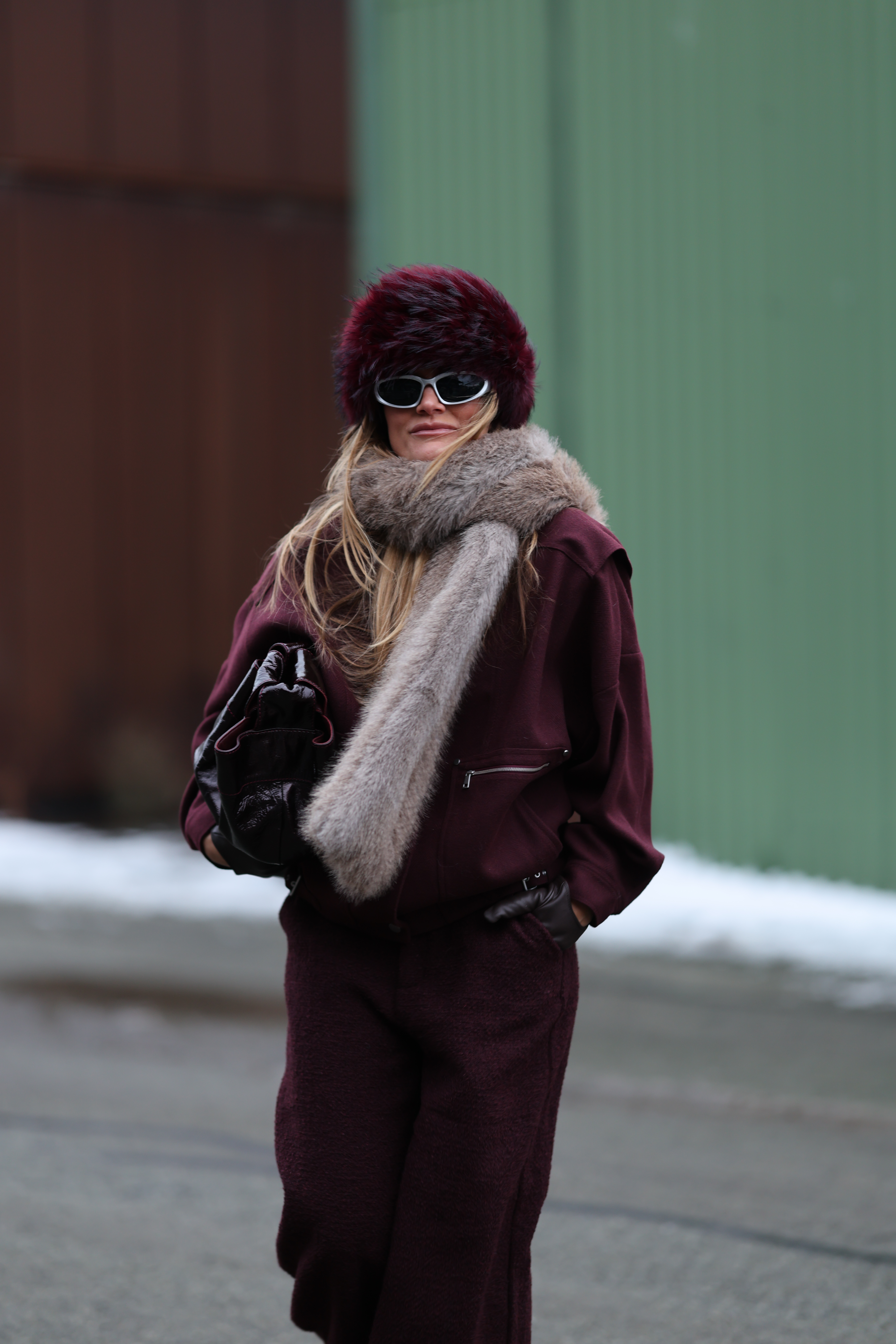 a guest at Copenhagen Fashion Week wearing a burgundy fur hat