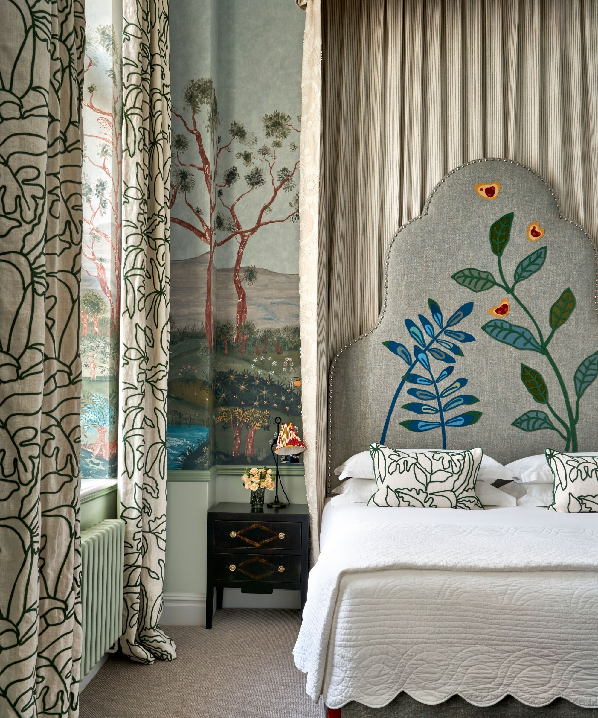 grey blue hotel bedroom with a large sculptural headboard embroidered with florals and leaves and a canopy hung above