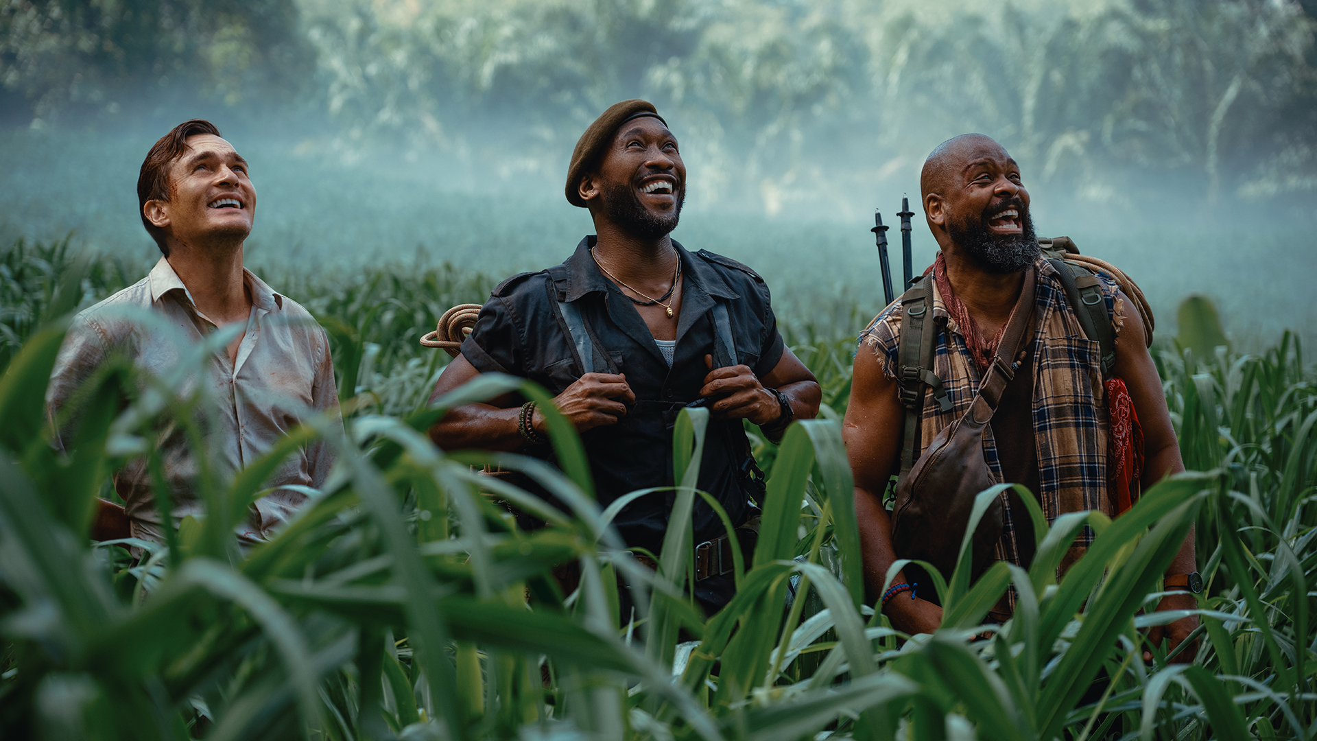 Three member of Zora's team smiling as they look at an off-screen dinosaur in Jurassic World Rebirth