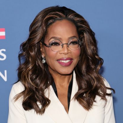 Headshot of Oprah Winfrey wearing white, set against a blue background