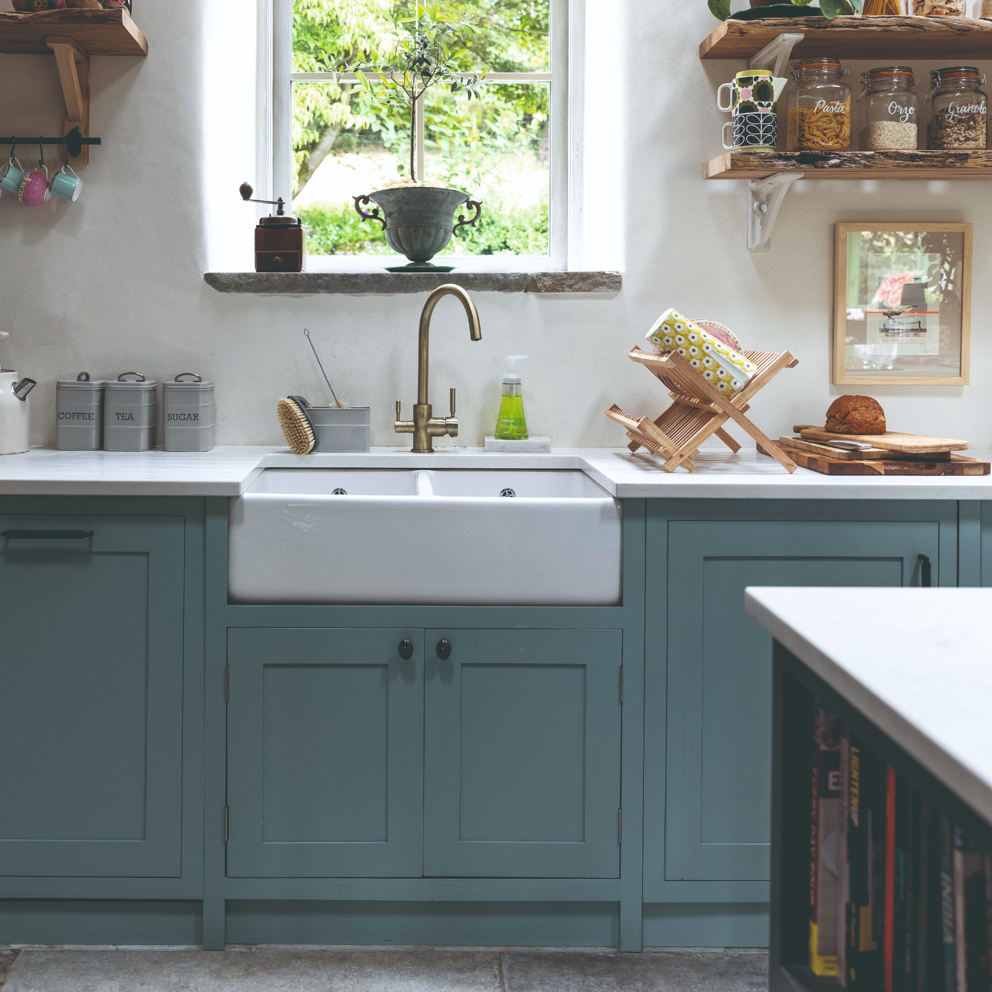 A kitchen with a large sink, blue kitchen cabinets and open shelving storage