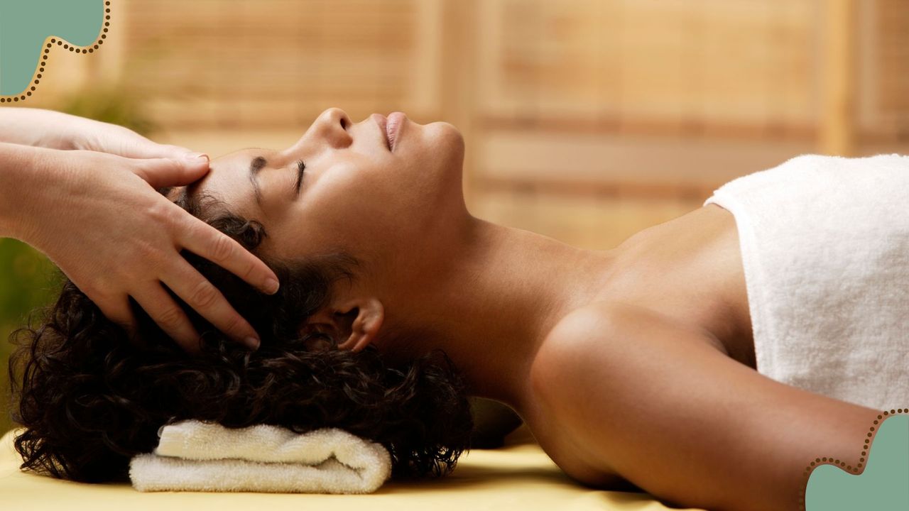 A woman wearing a towel in a spa having a head massage during a scalp facial 