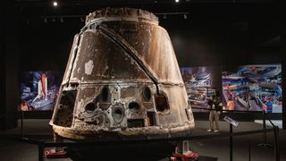 a charred space capsule on display in a museum