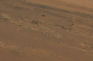 A zoomed-in view of Ingenuity's photo reveals the Perseverance rover off in the distance.