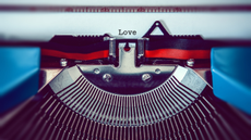 A typewriter types the word 'Love' on a piece of paper